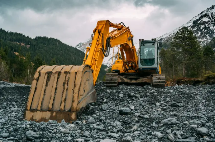 yellow and black excavator on rocky ground